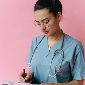 a young nurse writing on a clipboard