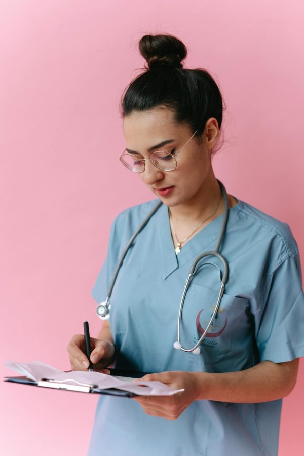 a young nurse writing on a clipboard